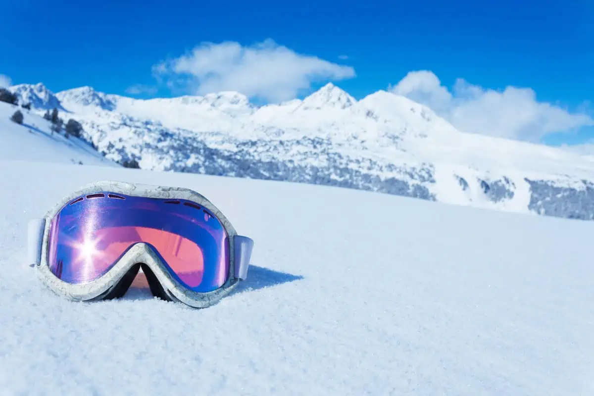 Gafas de esquí en la nieve primer plano fondo de montaña recreación activa  deportes de invierno en los rayos del sol