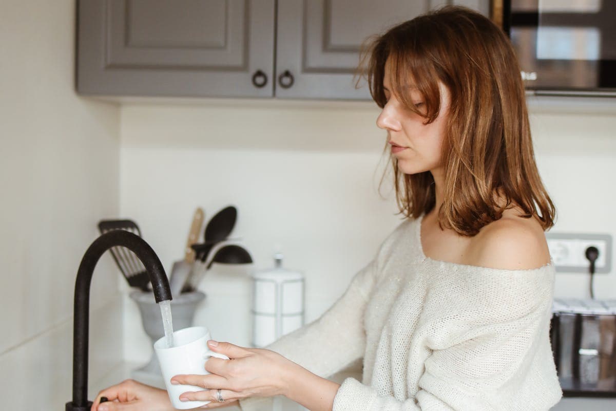 Mujer echando en un vaso agua del grifo