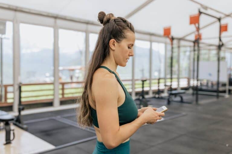 mujer usando teléfono móvil entre series de entrenamiento