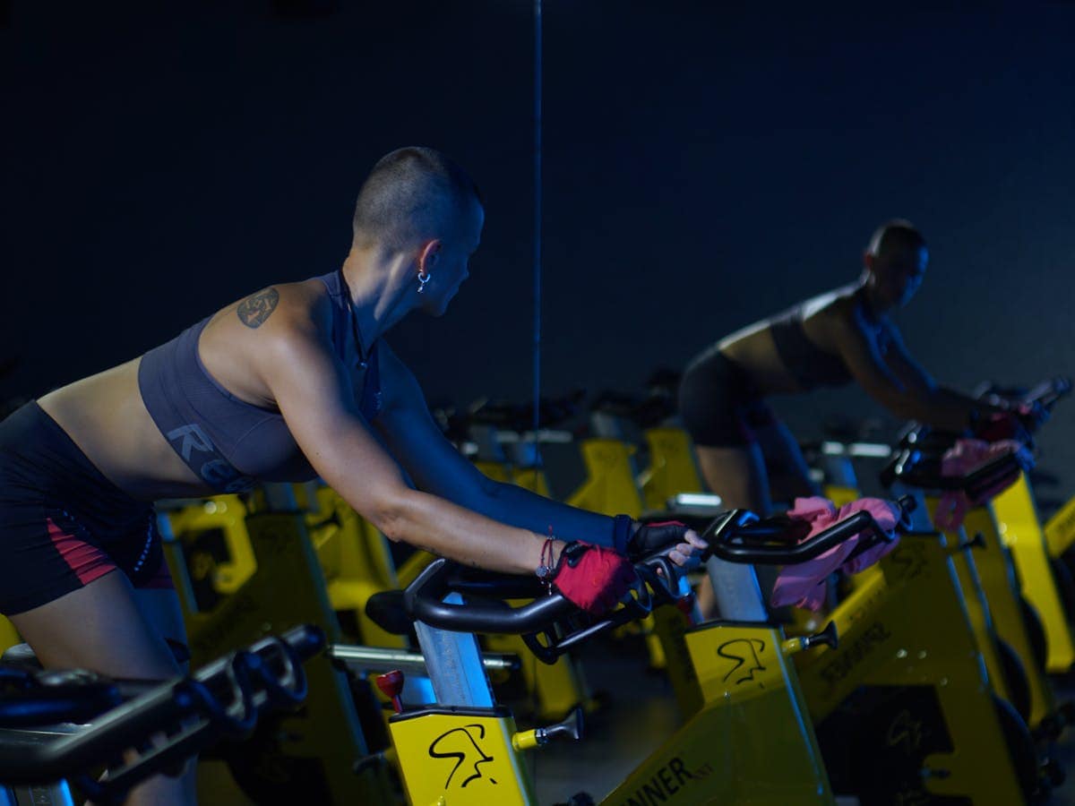 Bici estática: 3 beneficios para la salud Apasionada del ciclo indoor frente al espejo.